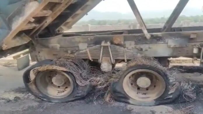 जमशेदपुर के हुरलुंग पुल के पास चलती हाईवा में लगी आग के बाद सड़क किनारे खड़ा वाहन और मौके पर जुटे स्थानीय लोग